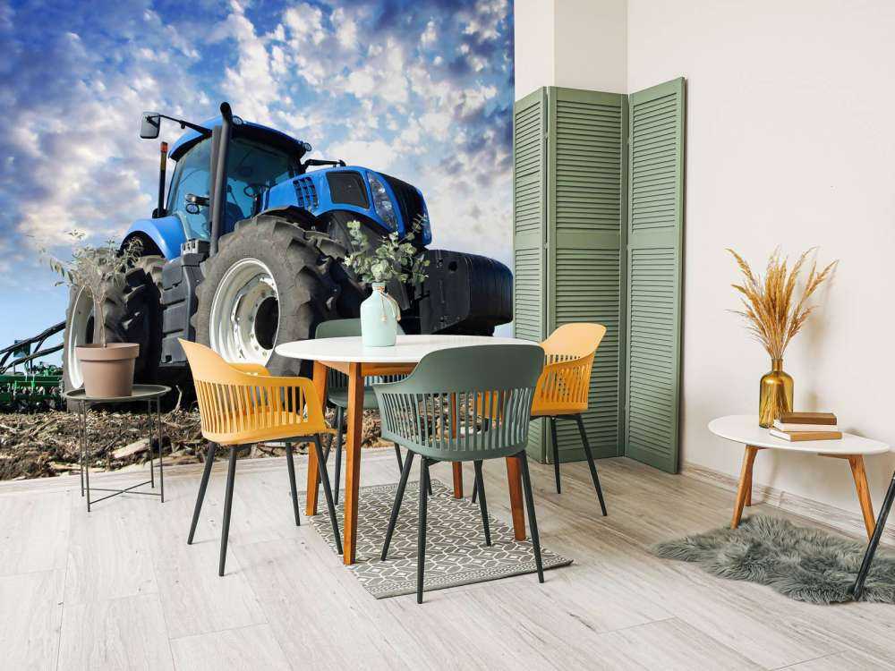 Grote blauwe tractor onder een bewolkte hemel