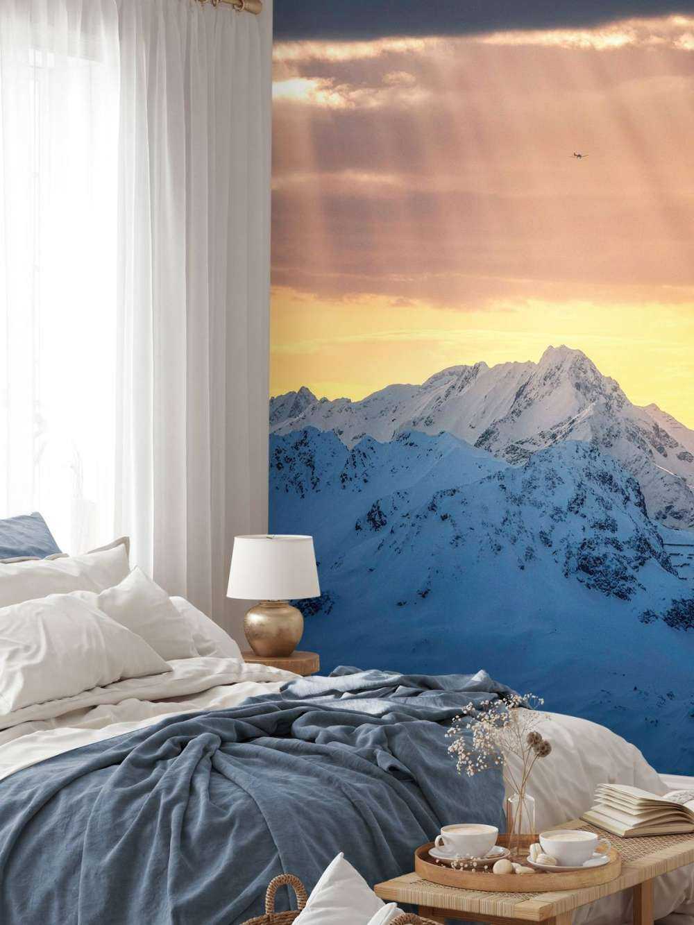 Zonnestralen boven besneeuwde bergtoppen