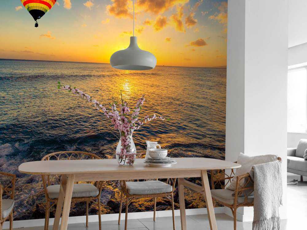 Luchtballon boven zee bij zonsondergang