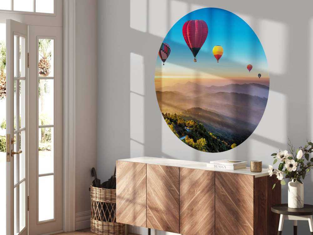 Grote groep luchtballonnen boven een mistig berglandschap
