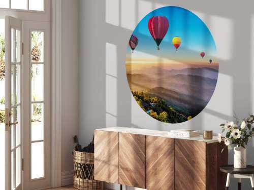 Grote groep luchtballonnen boven een mistig berglandschap