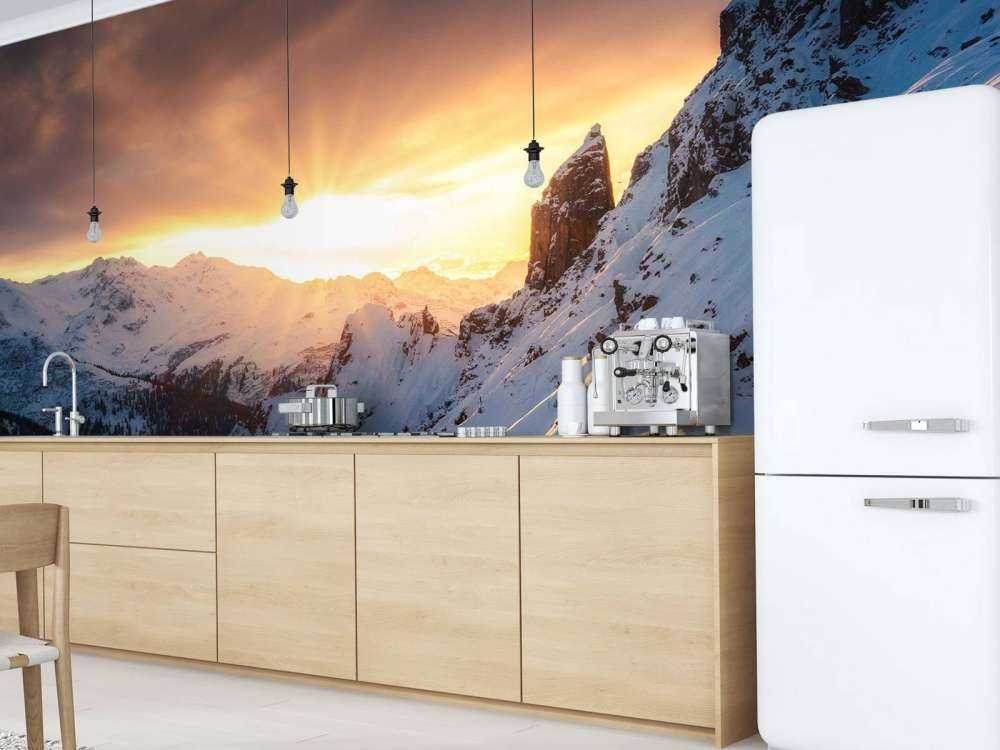 Avondzon achter besneeuwde bergtoppen