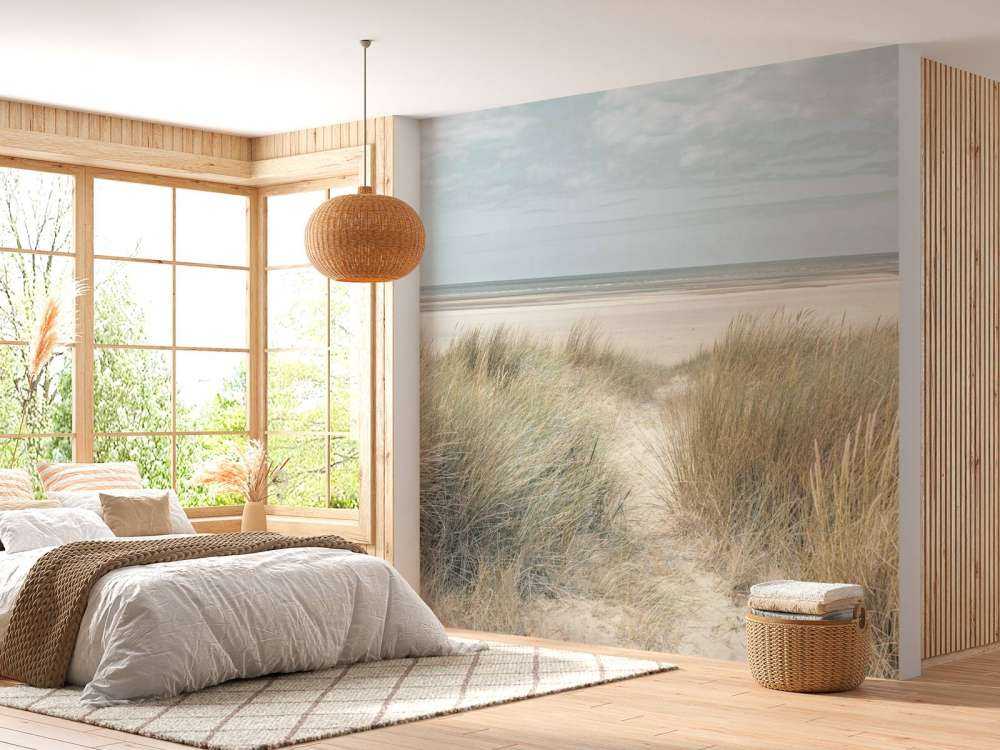 Grassy sand dunes on the sea coast under blue sky