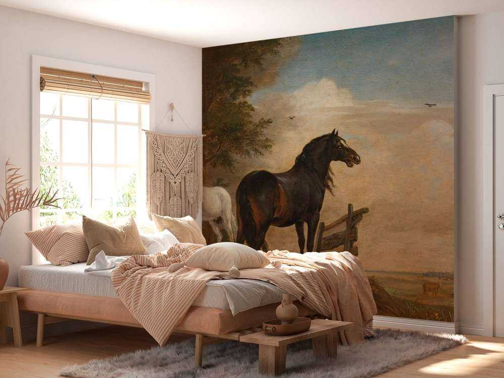 Twee paarden in de weide bij een hek