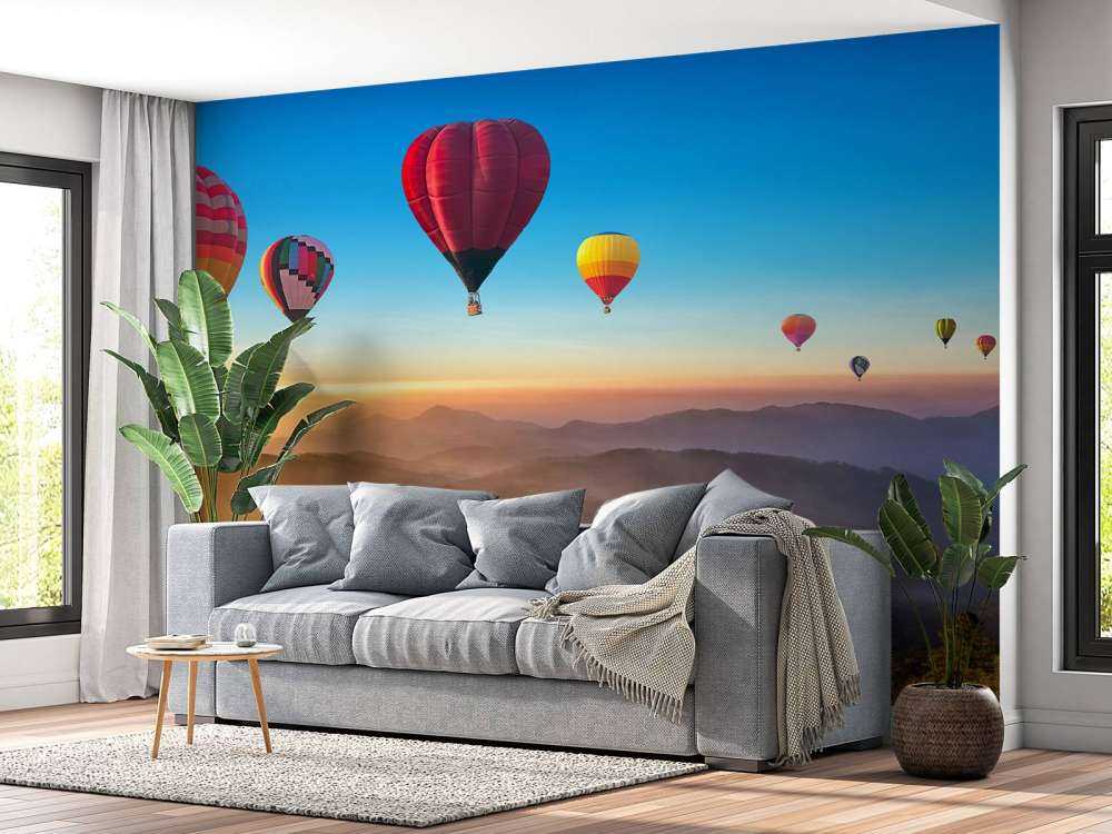 Grote groep luchtballonnen boven een mistig berglandschap