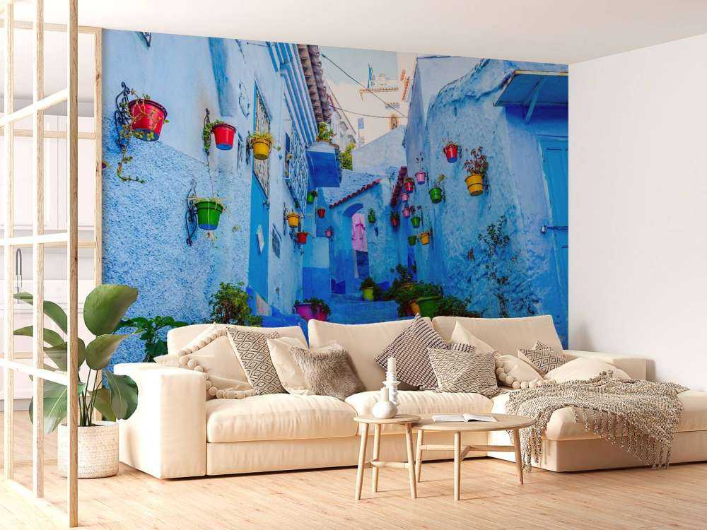 Blauwe straat met kleurrijke bloemenemmers in Marokko