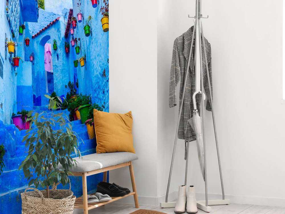 Blauwe straat met kleurrijke bloemenemmers in Marokko