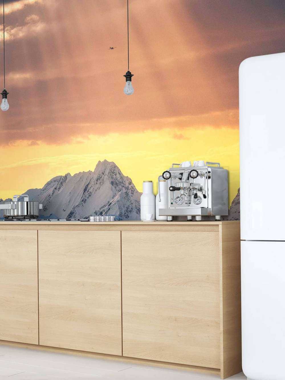 Zonnestralen boven besneeuwde bergtoppen