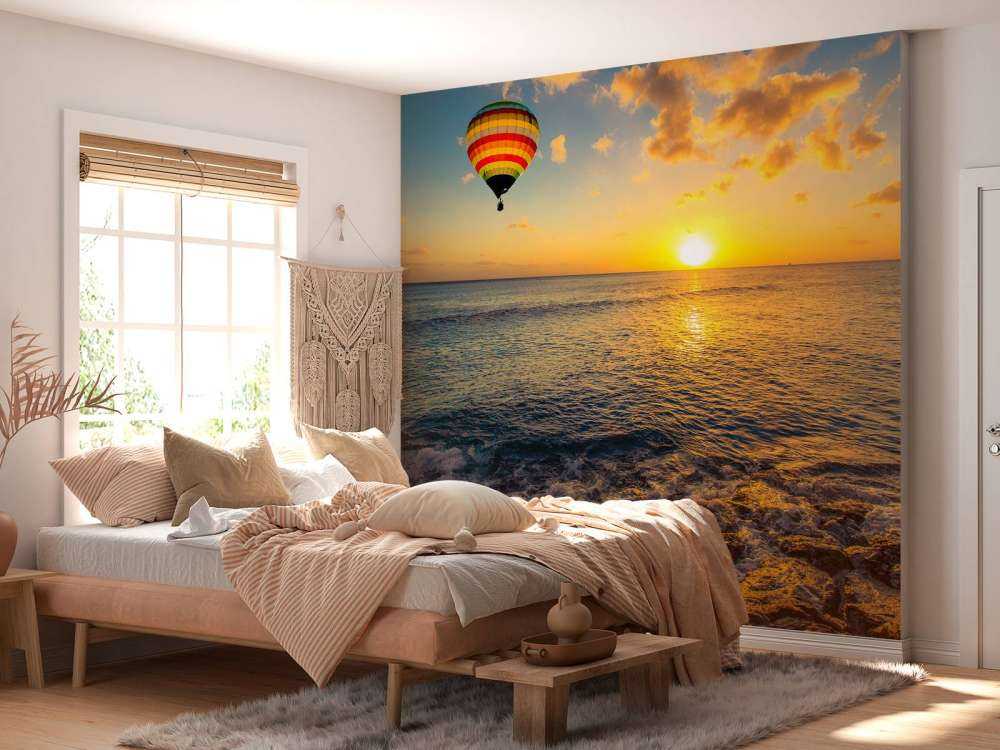 Luchtballon boven zee bij zonsondergang