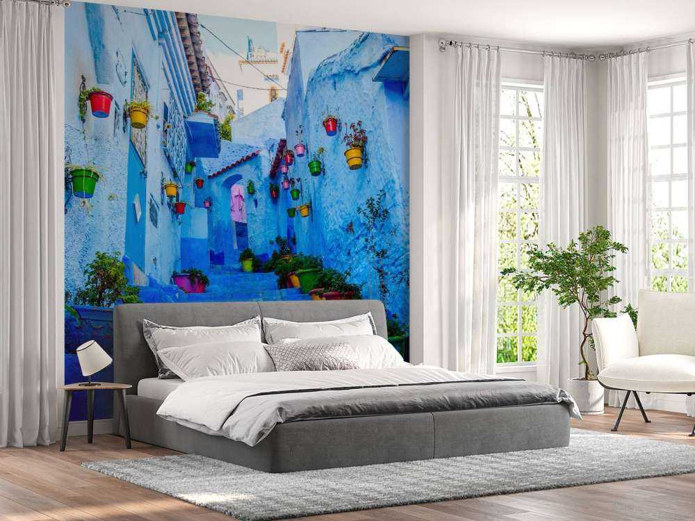 Blauwe straat met kleurrijke bloemenemmers in Marokko