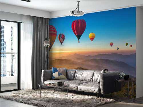 Grote groep luchtballonnen boven een mistig berglandschap