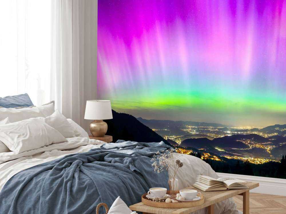 Noorderlicht boven verlichte bergstad
