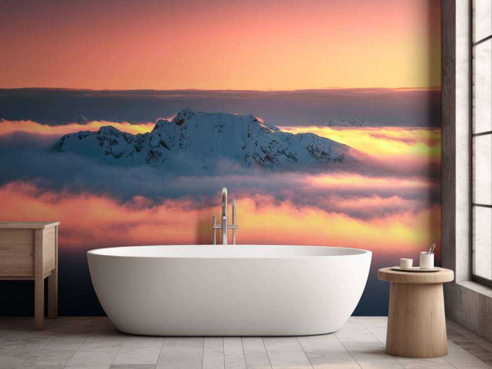 Besneeuwde bergtop in wolkenzee