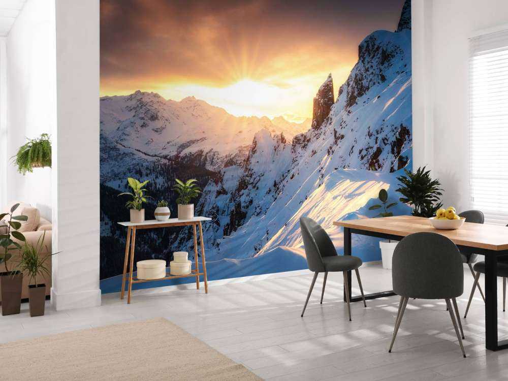 Avondzon achter besneeuwde bergtoppen