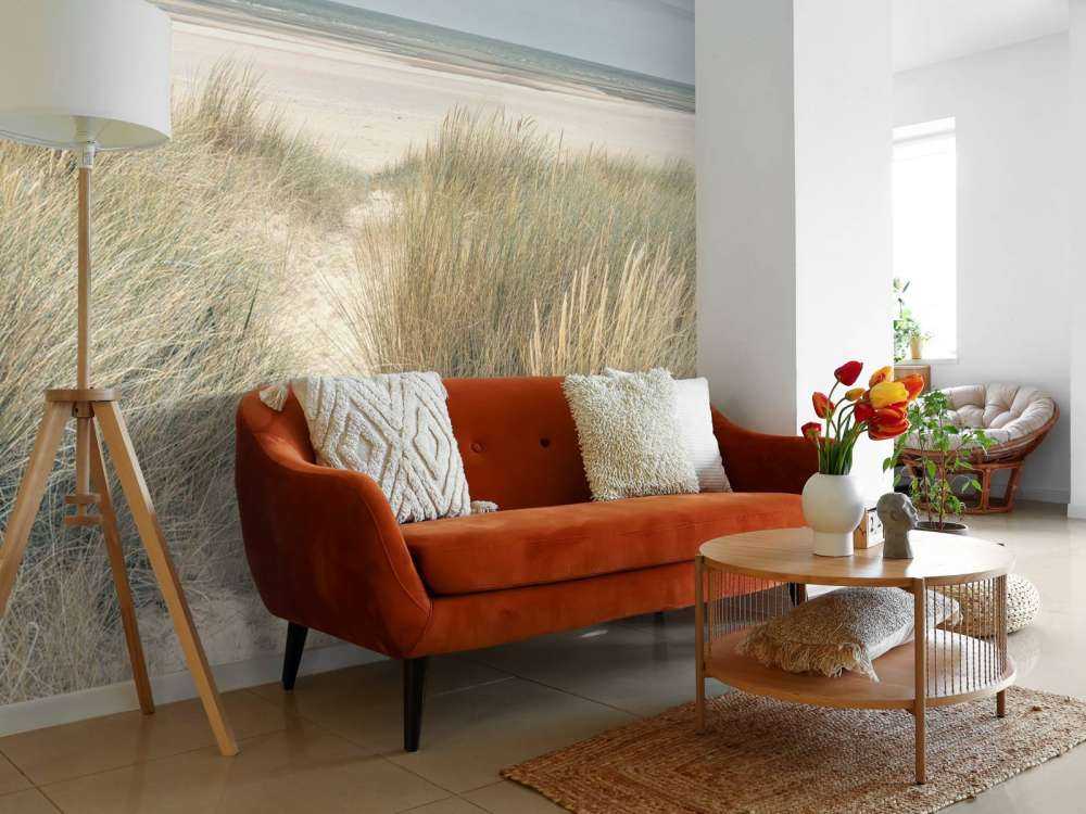 Grassy sand dunes on the sea coast under blue sky
