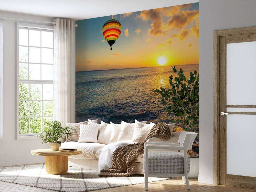 Luchtballon boven zee bij zonsondergang